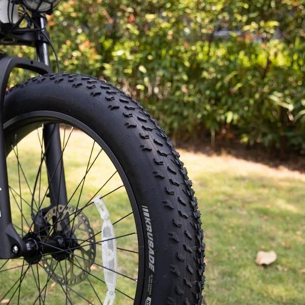 Pneu de vélo noir avec profil rugueux. Marque : KRUSADE. Fait partie de la roue avant.