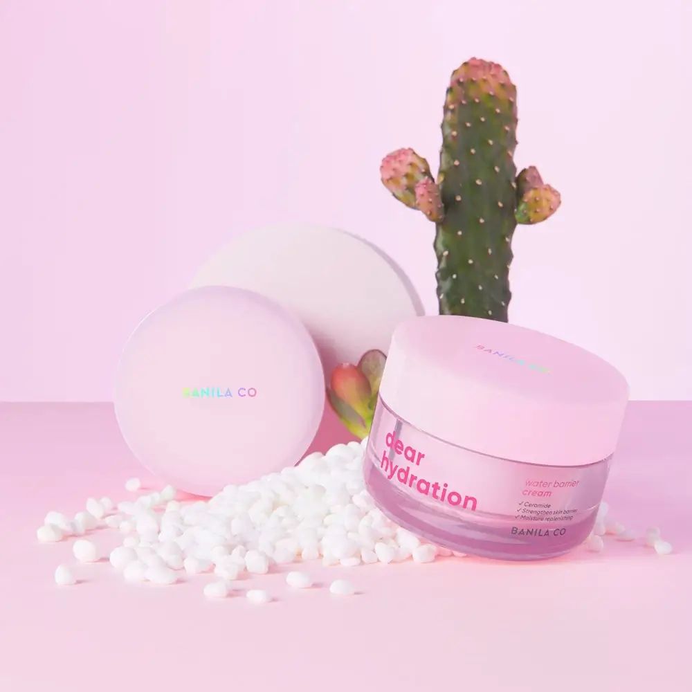 Potje en deksel naast cactus en witte bolletjes. Op potje staat "dear hydration" en "BANILA CO".