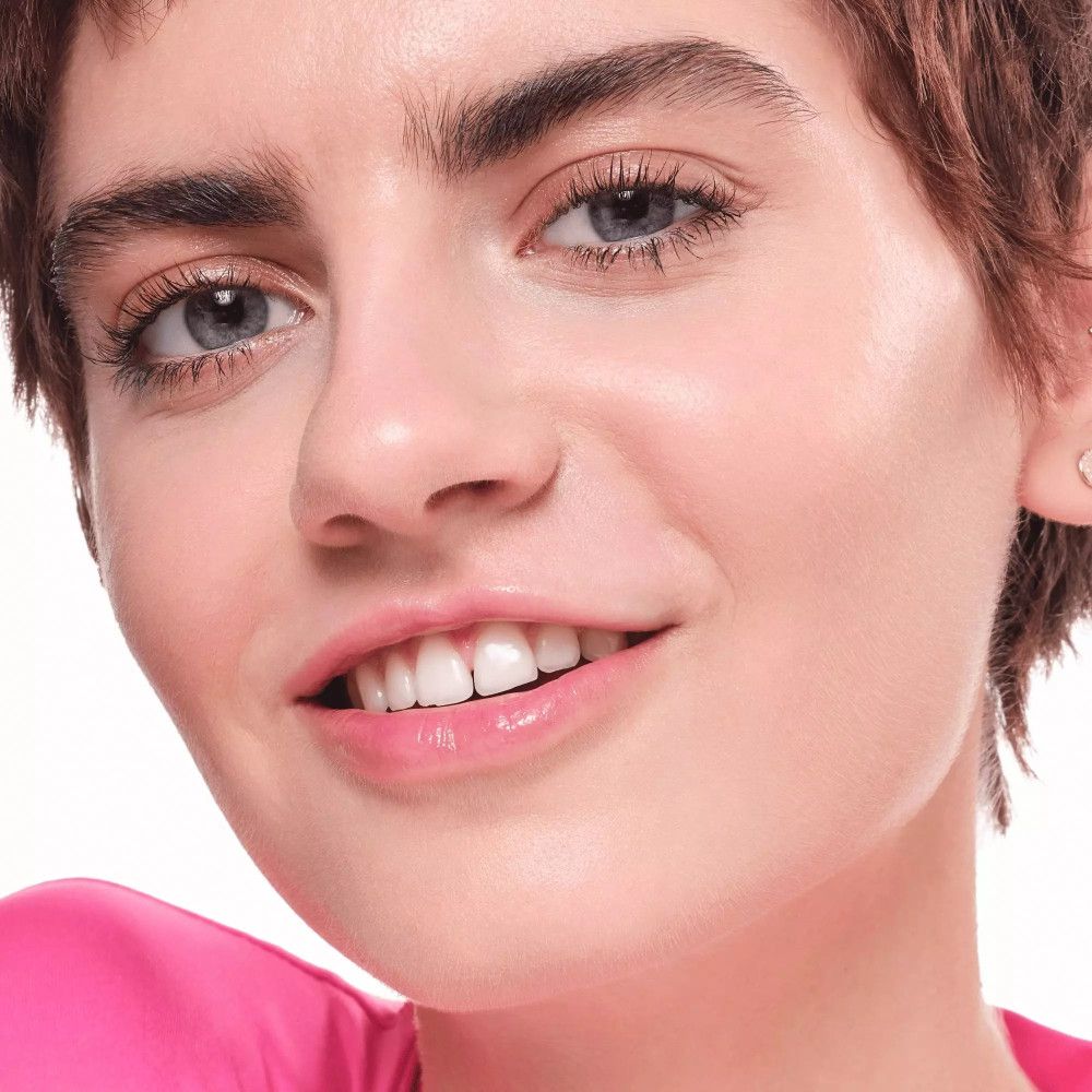 Portrait d'une femme à la peau claire. Elle porte du maquillage, dont du correcteur.