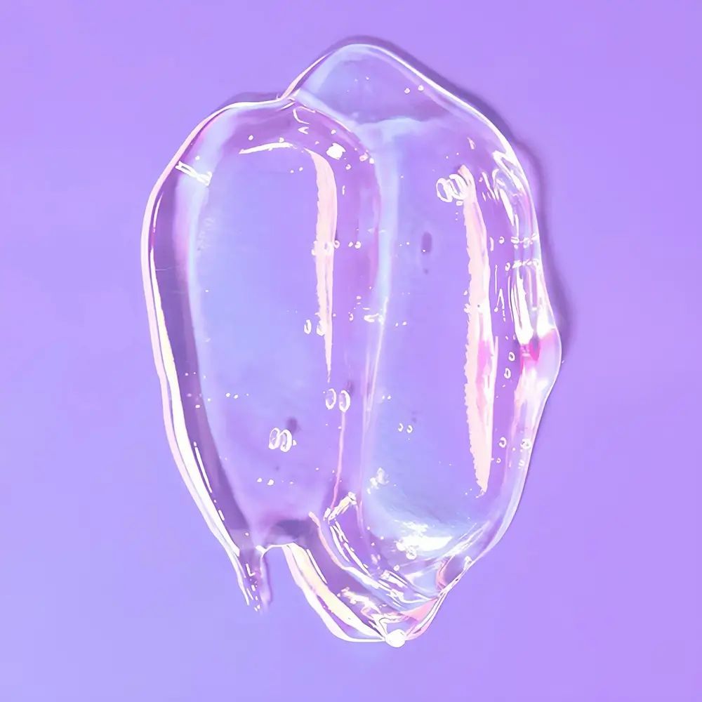 Éclaboussure de gel clair sur fond violet. Quelques bulles visibles. Forme irrégulière.