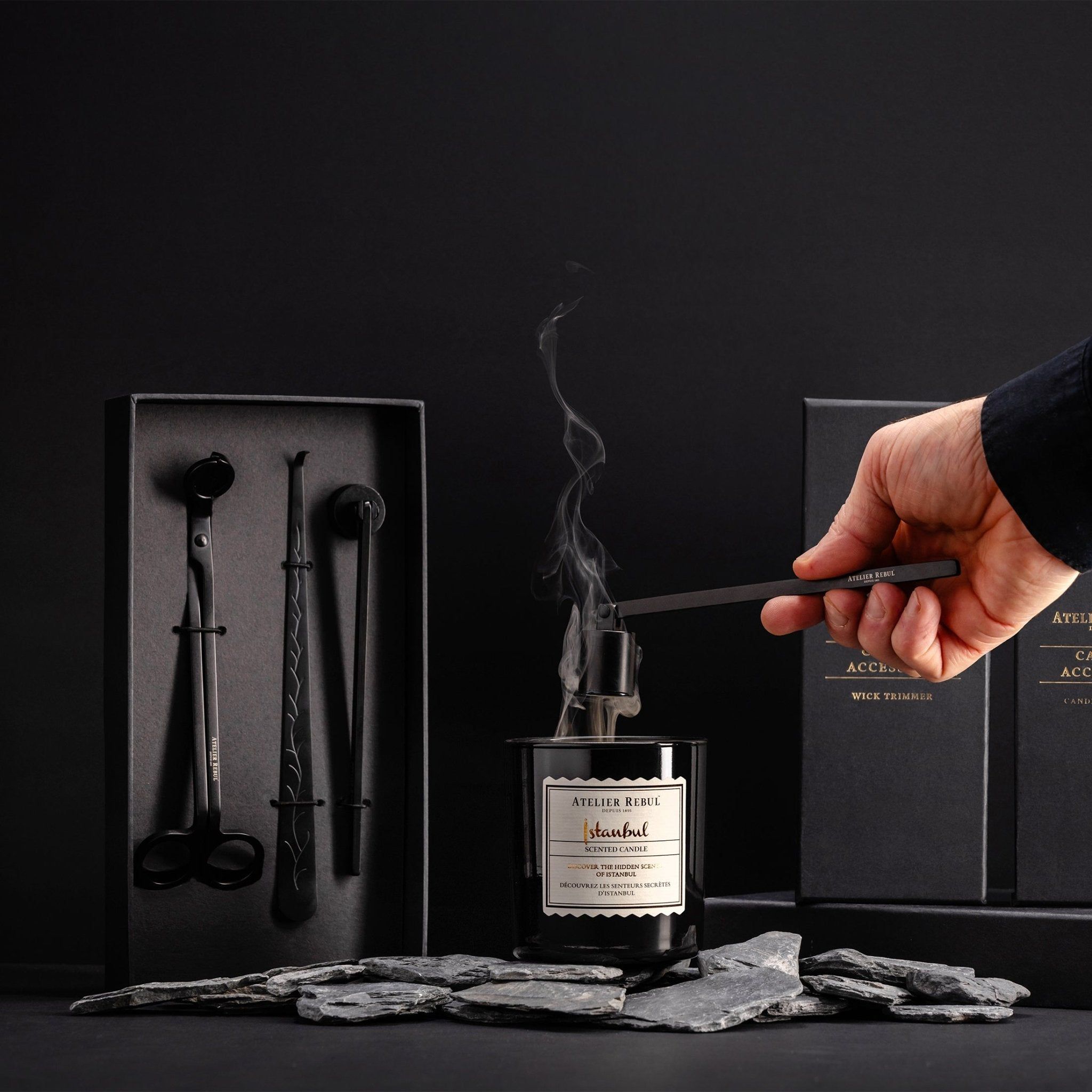 Un set d'entretien pour bougies Atelier Rebul avec bougie noire, coupe-mèche, releveur de mèche et éteignoir.