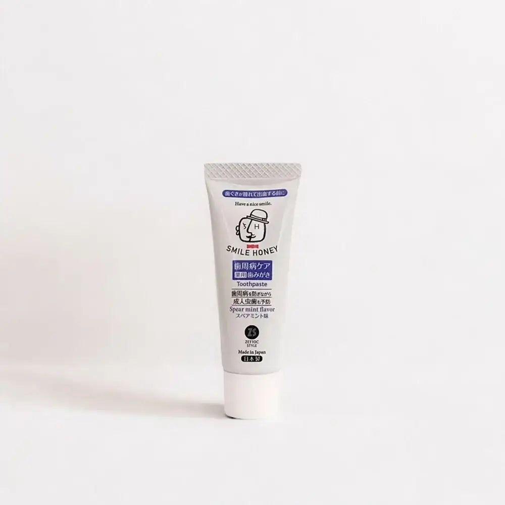 Tandpastatube "SMILE HONEY". Grijze tube, witte dop. "Spear mint flavor" zichtbaar.