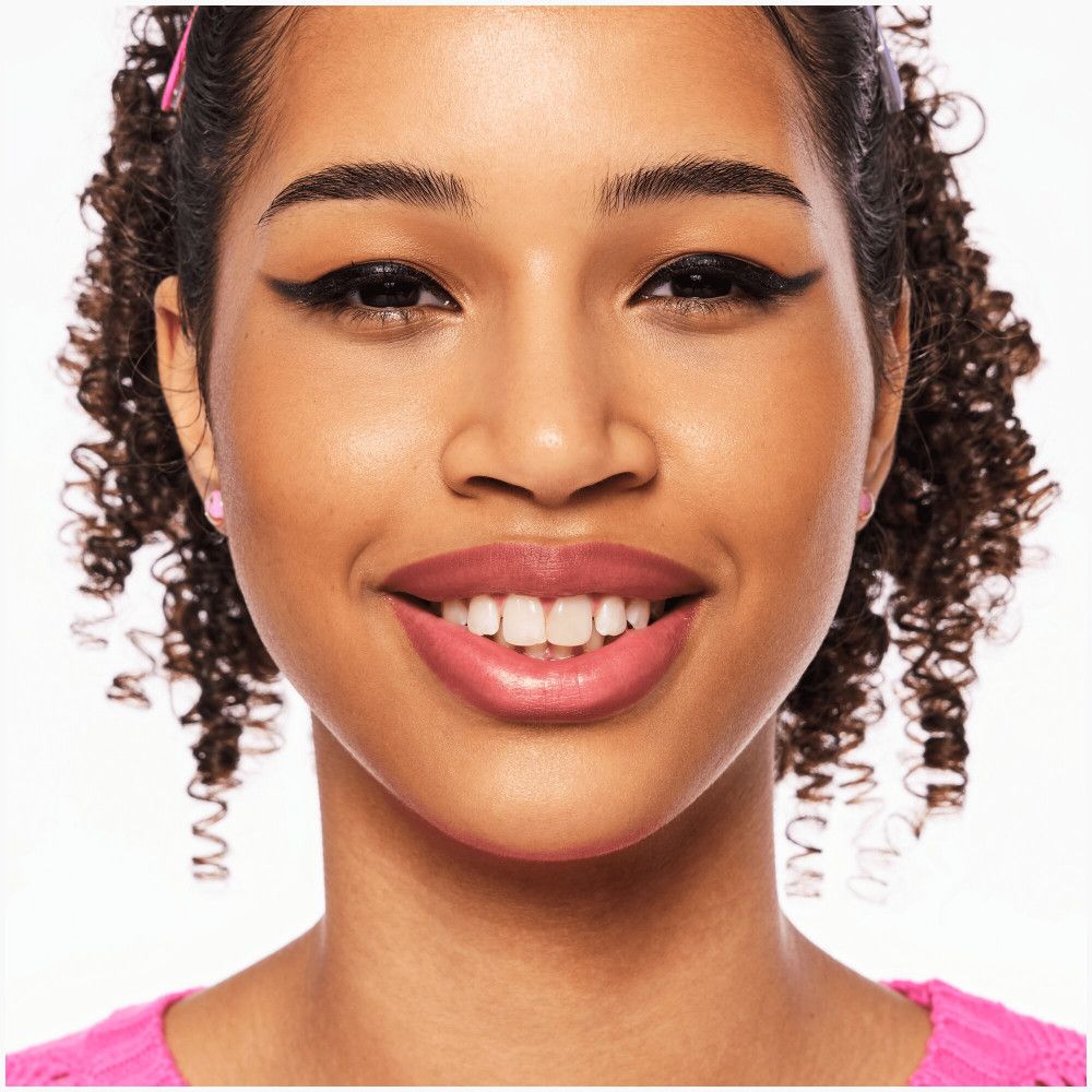 Portret van een lachende vrouw. Zwarte eyeliner, roze lippenstift, krullend haar.