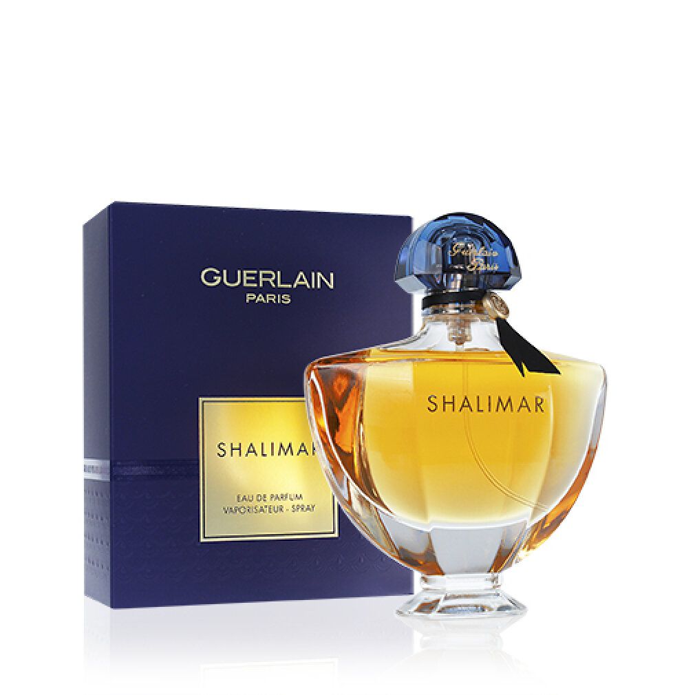 Flacon de parfum à côté de la boîte. Flacon avec bouchon bleu, liquide doré et inscription Shalimar.