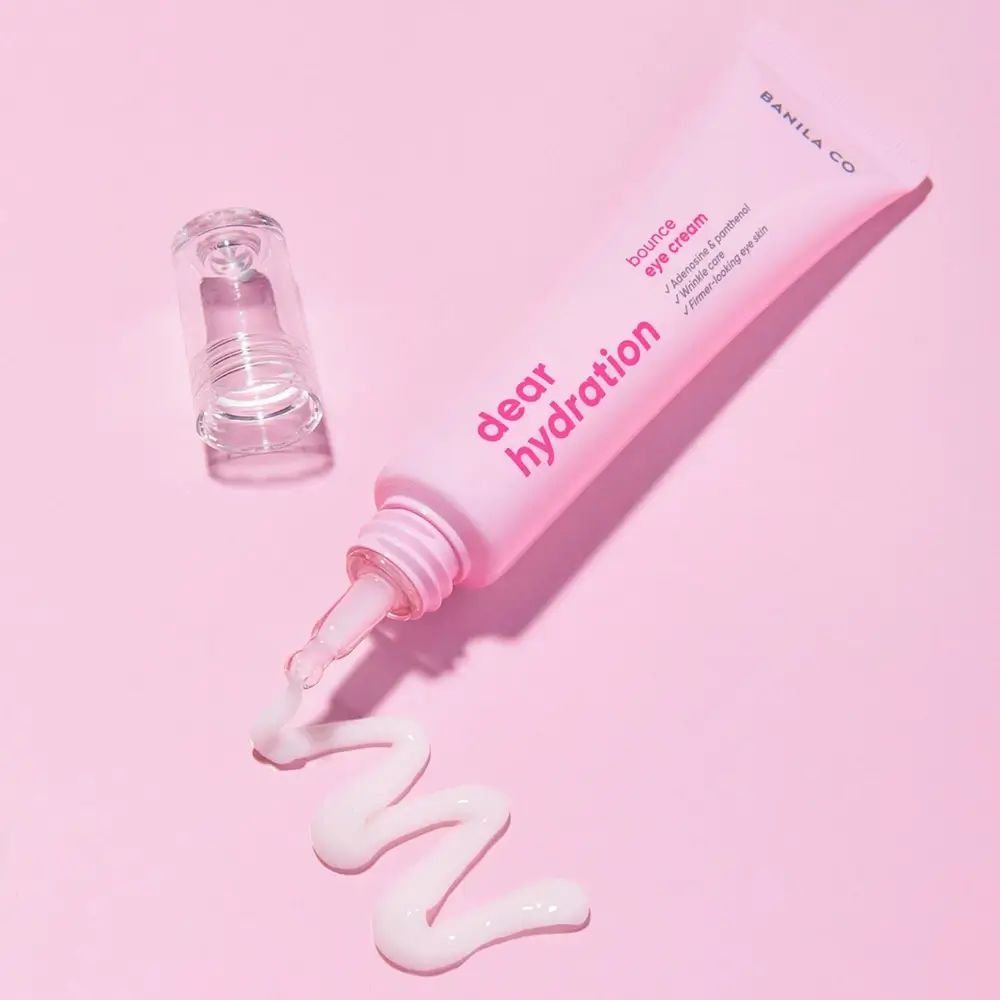 Tube de crème pour les yeux rose avec applicateur. La crème est pressée hors du tube.