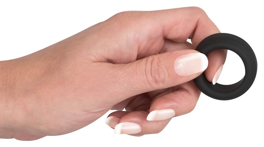 Anneau noir et souple en silicone tenu par une main.