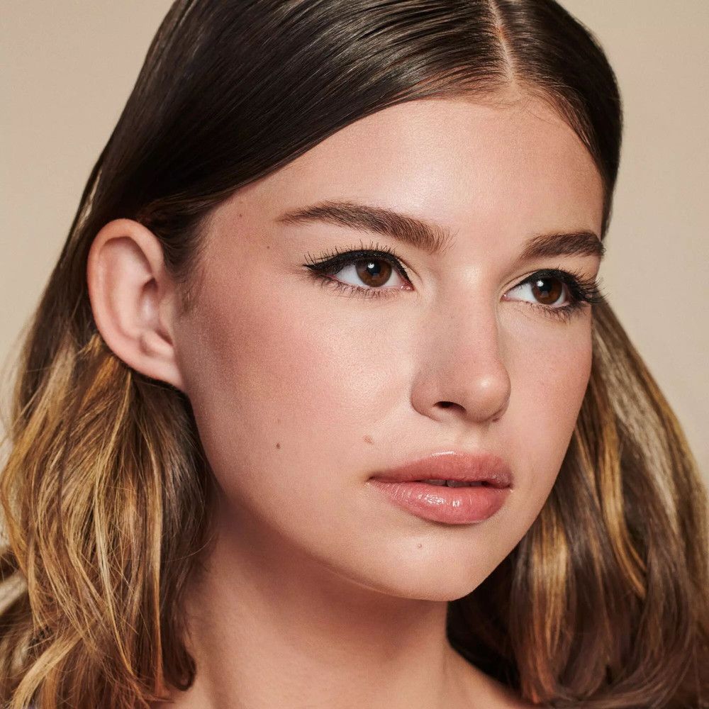 Portret van een vrouw met eyeliner en valse wimpers. Ze heeft bruine ogen en lang golvend haar. De eyeliner is zwart.