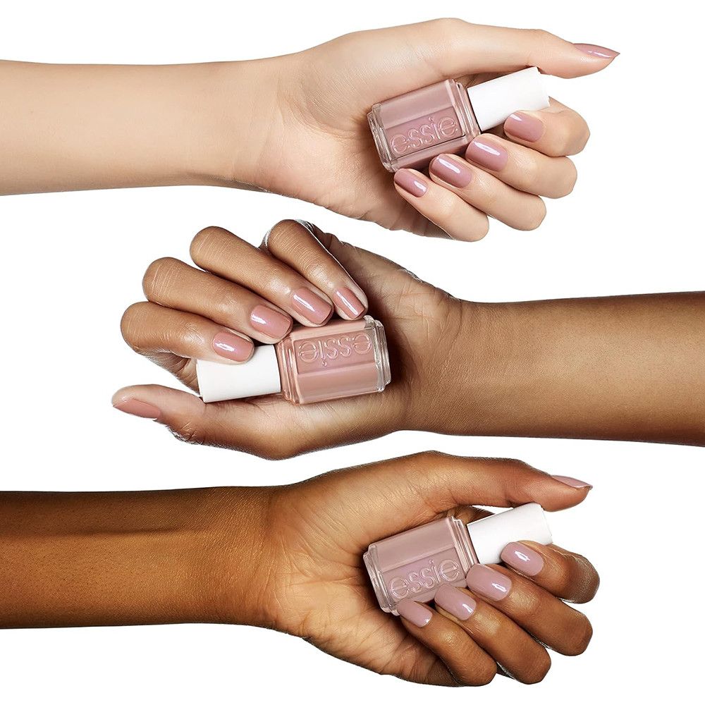 Trois mains aux teints variés tiennent des flacons de vernis à ongles rose. La marque 'essie' est visible.