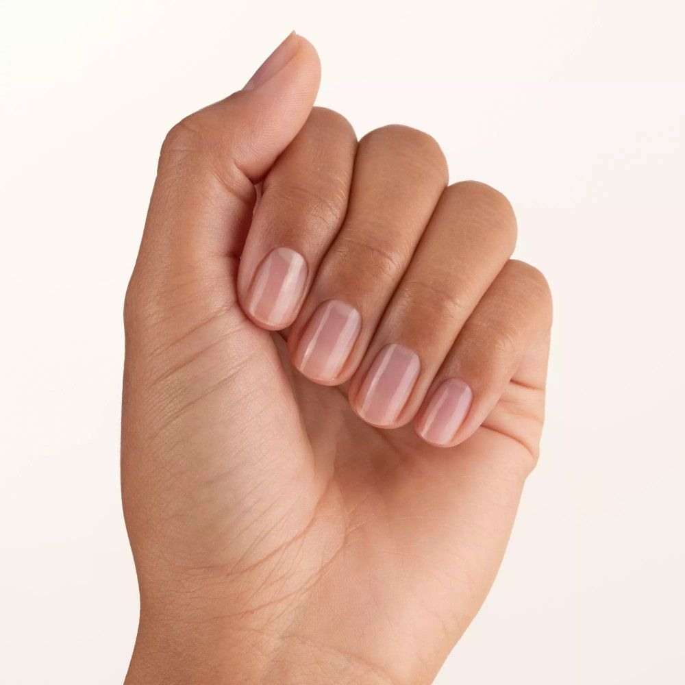Hand met vijf gelakte nagels. Nagels zijn kort en ovaal van vorm. De nagellak is transparant.