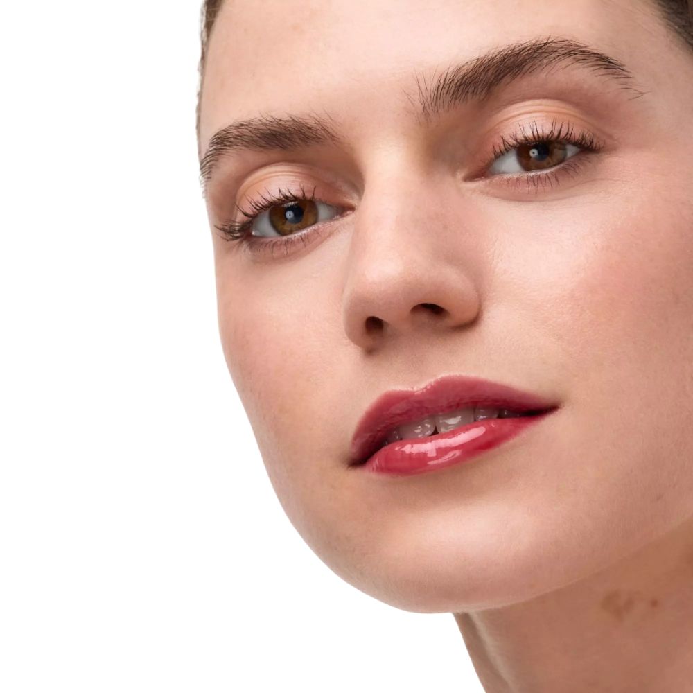 Close-up van een gezicht met lipolie. Vrouw met bruine ogen en lippenstift. Witte achtergrond.