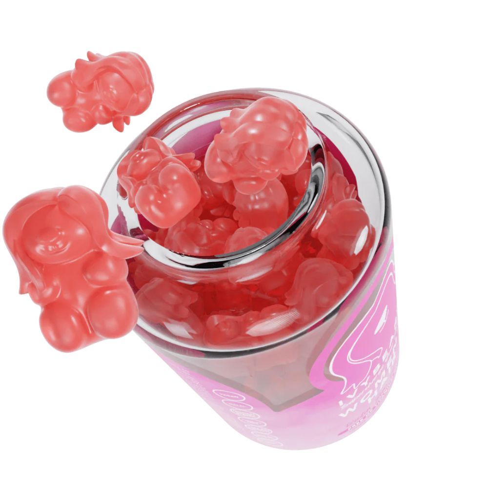 Verre avec oursons gélifiés roses. Quelques oursons gélifiés en dehors du verre. Vue de dessus.