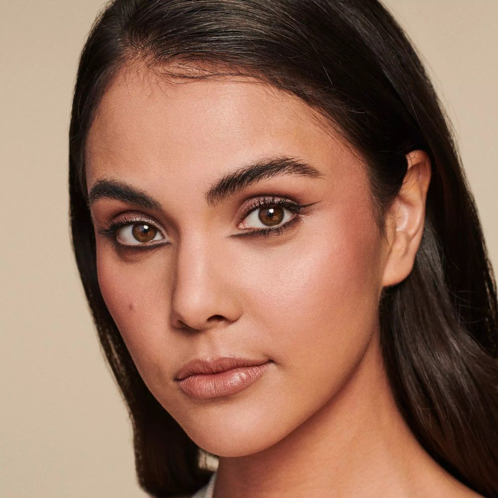 Gros plan d'un visage maquillé. Sourcils foncés, eye-liner, joues et lèvres rosées.