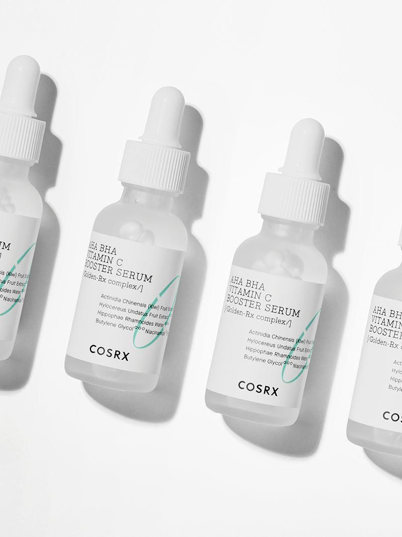 Quatre flacons de sérum avec pipettes. Inscription : AHA BHA Vitamin C Booster Serum. Marque : COSRX.