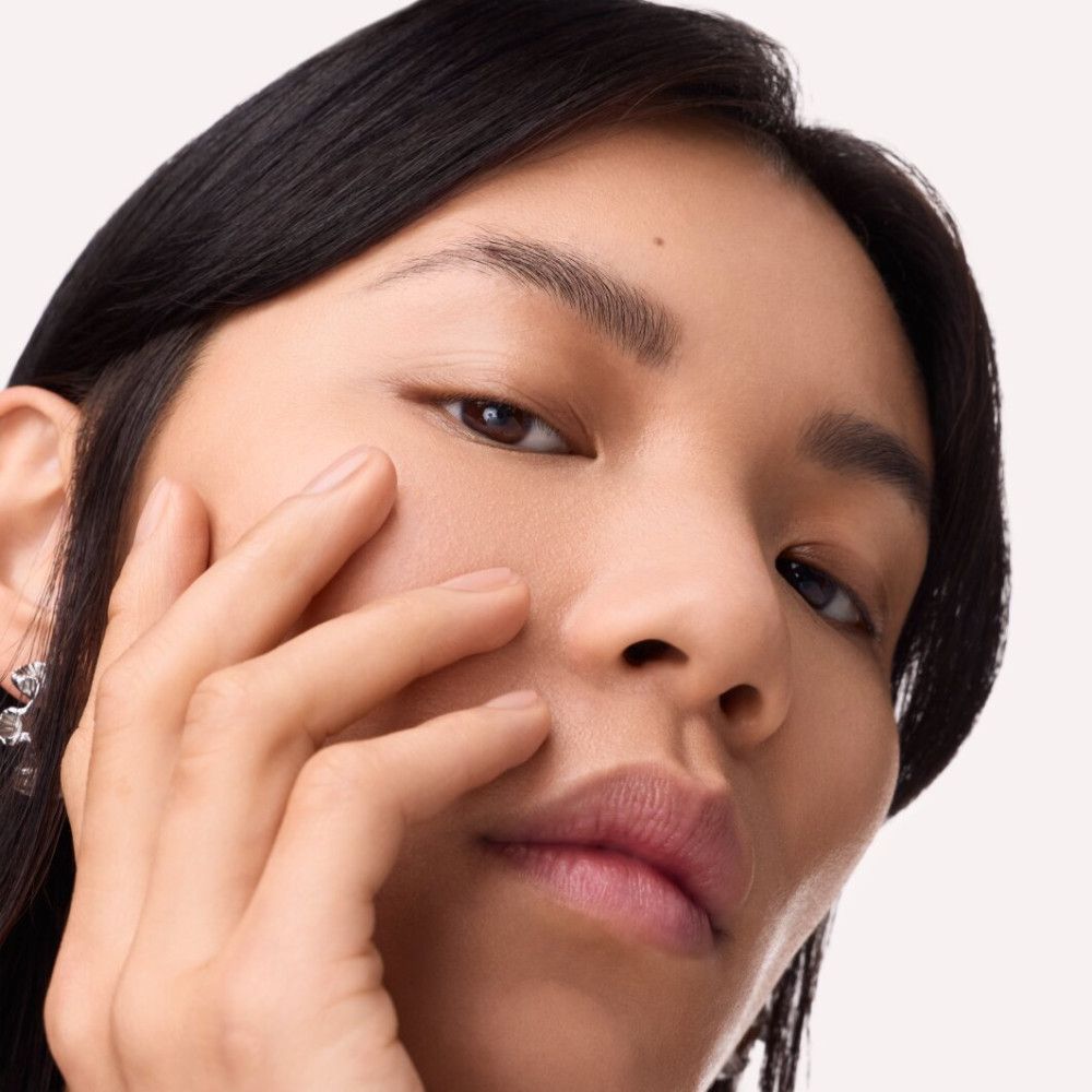 Gros plan d'une personne touchant sa joue. Accent sur les sourcils et la peau. Lumière naturelle.