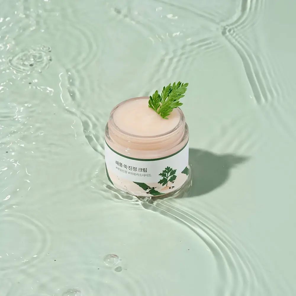 Crèmepot met tekst en een takje. Op waterachtergrond.