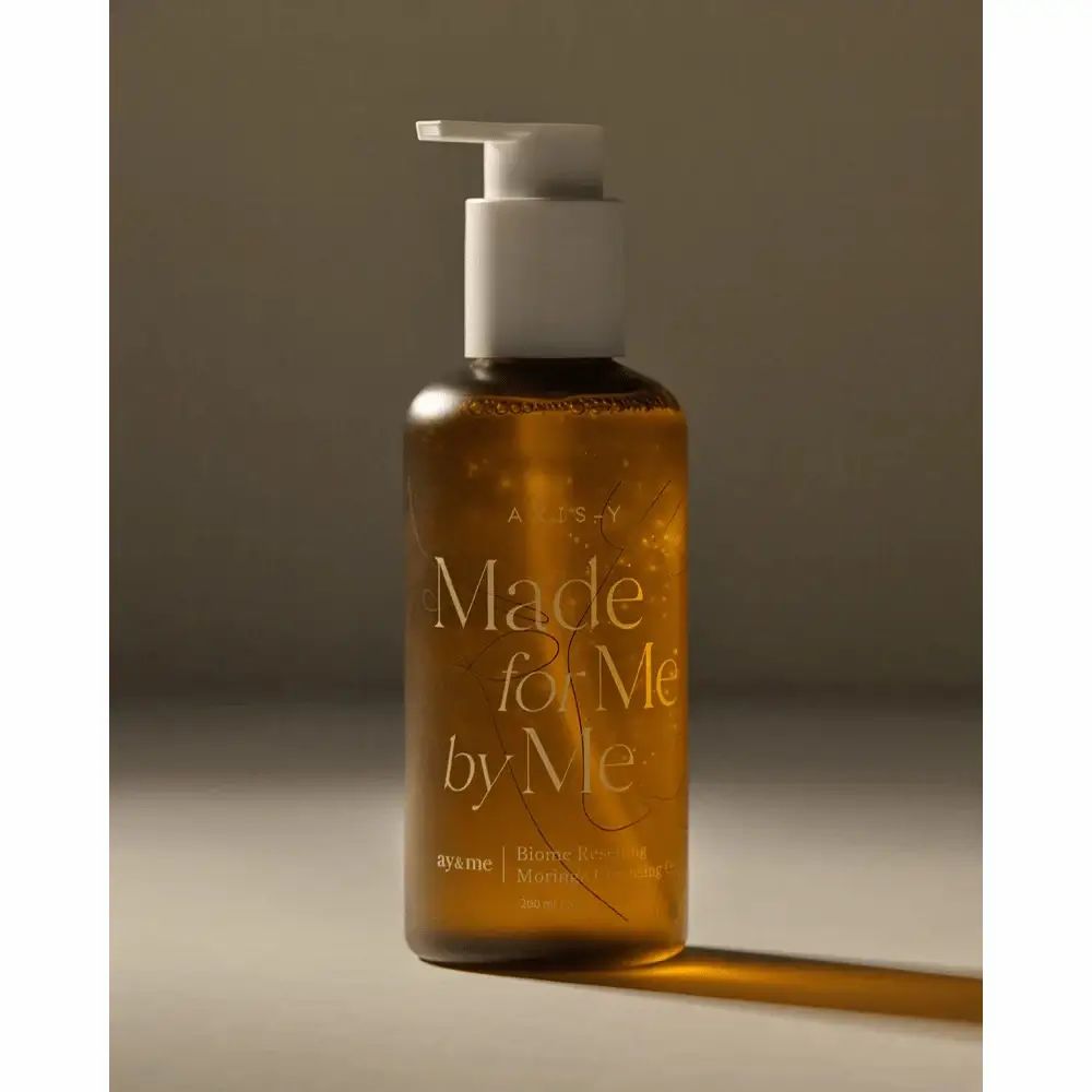 Bruine fles met witte pomp. Opschrift: AXIS-Y, Made for Me by Me, Biome Resetting Moringa Cleansing Oil.