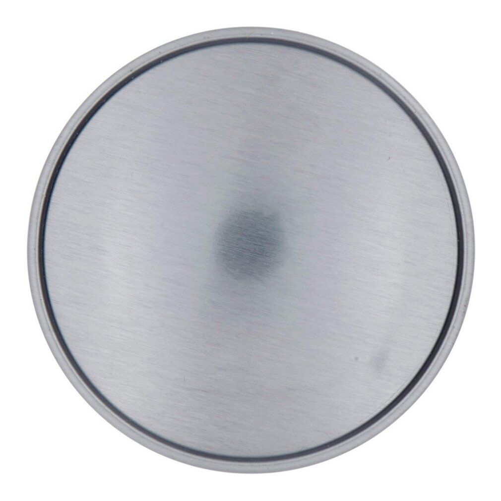 Metalen, ronde deksel. Zwarte rand. In het midden een klein, donker puntje.