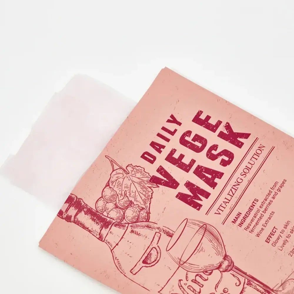 Roze masker verpakking, gedeeltelijk geopend. Opdruk: DAILY VEGE MASK, wijn illustratie, ingrediënten, effect. Wit masker zichtbaar.