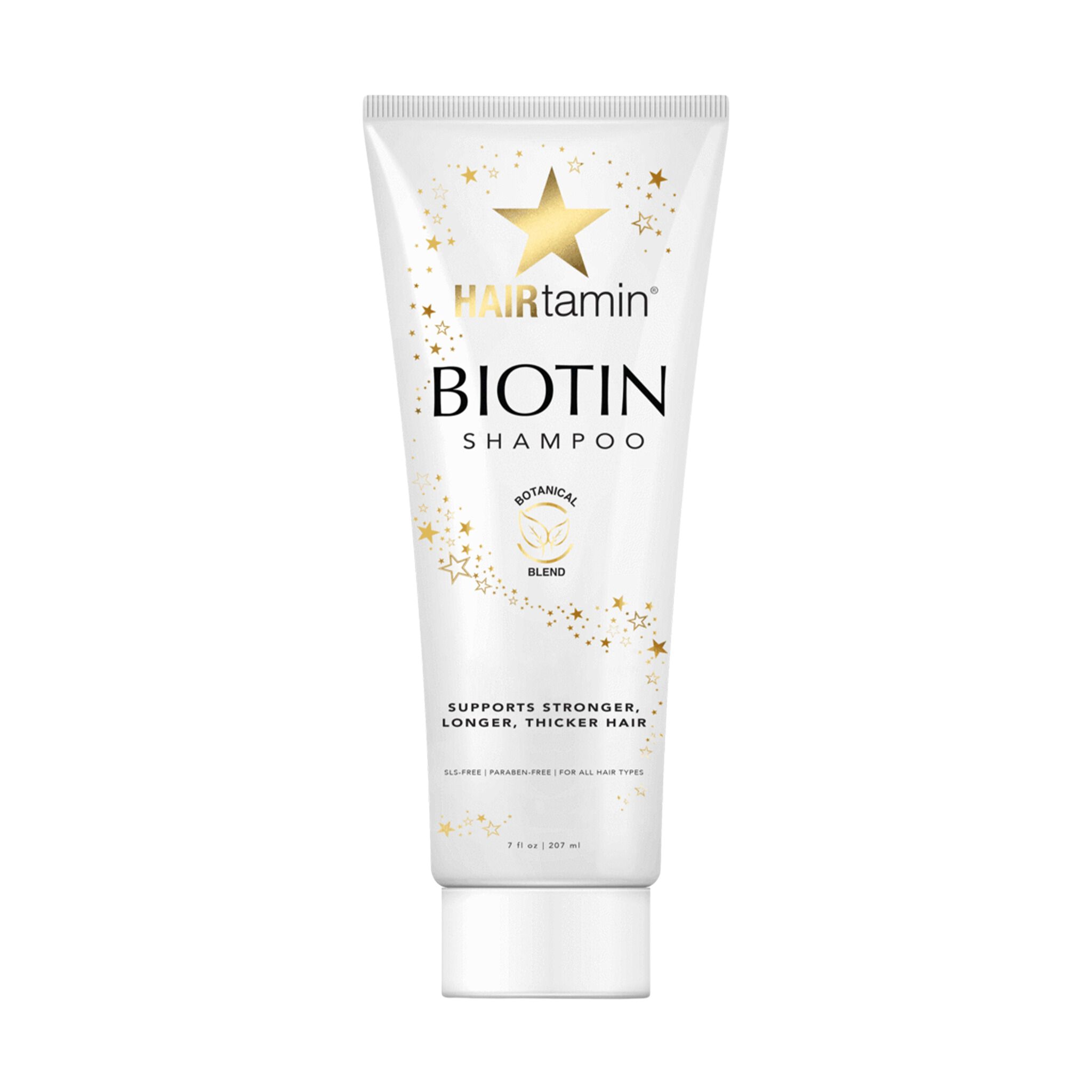 Tube blanche "HAIRtamin Biotin Shampoo". Étoiles et texte "Botanical Blend". Texte : "Supports stronger, longer, thicker hair".