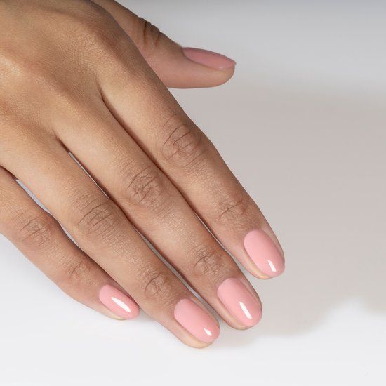 Main avec ongles peints en rose. Les ongles sont de forme ovale et brillants. Le fond est blanc.