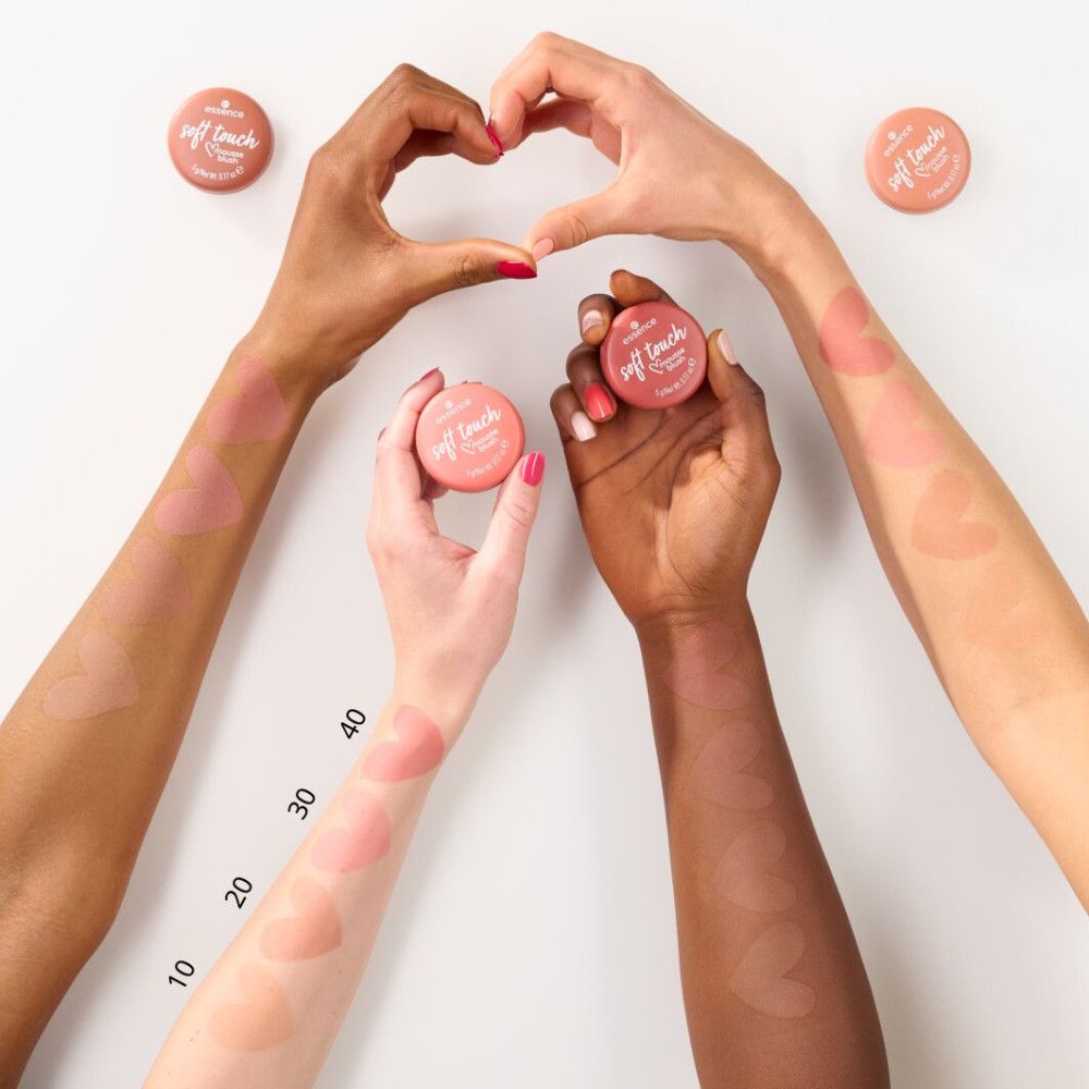 Mains tenant des pots de blush. Couleurs de blush appliquées sur les bras. Nom du produit et marque visibles.