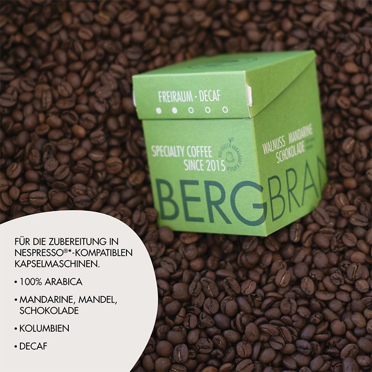 Boîte verte BERGBRAND sur grains de café. Texte : Freiraum-Decaf, Specialty Coffee, Walnuss Mandarine Schokolade. Autres textes.