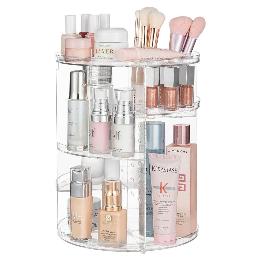 Organisateur cosmétique rotatif en acrylique transparent rempli de produits de beauté et de pinceaux.