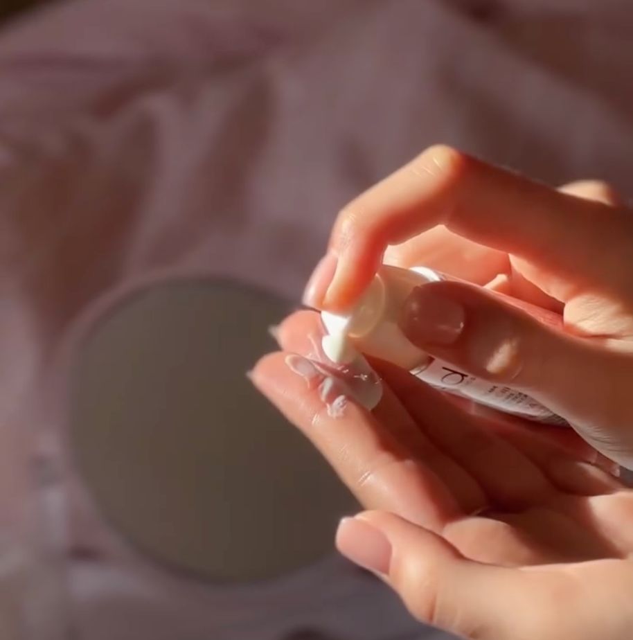 Crème solaire pressée d'un flacon blanc avec pompe sur la main.