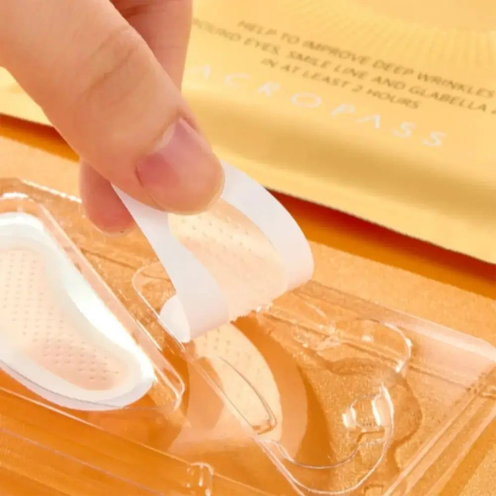 Hand die een retinol microkegel pleister van de beschermfolie trekt. De pleister is transparant.