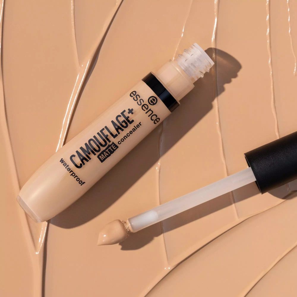 Tube de correcteur et applicateur sur fond clair. Inscription: CAMOUFLAGE+ matte concealer waterproof. Marque: essence.