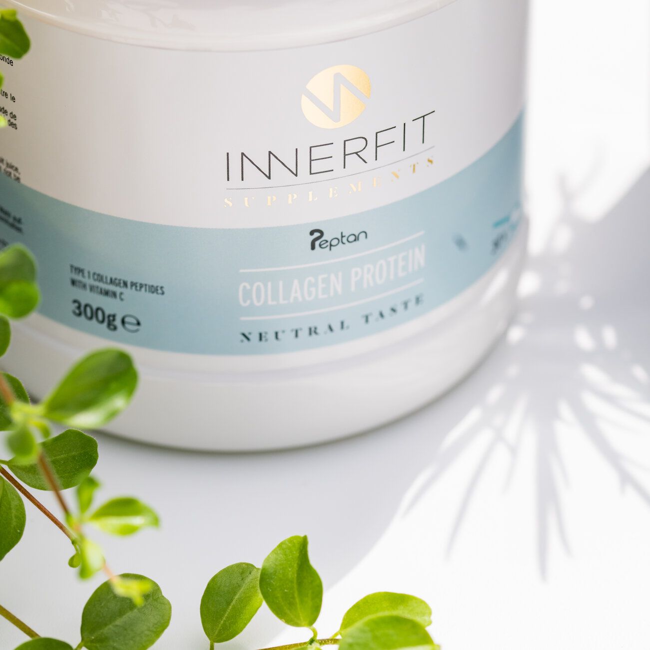 Pot blanc "Innerfit" avec logo doré et texte "Collagen Protein". Inscription "Neutral Taste". Feuilles vertes.