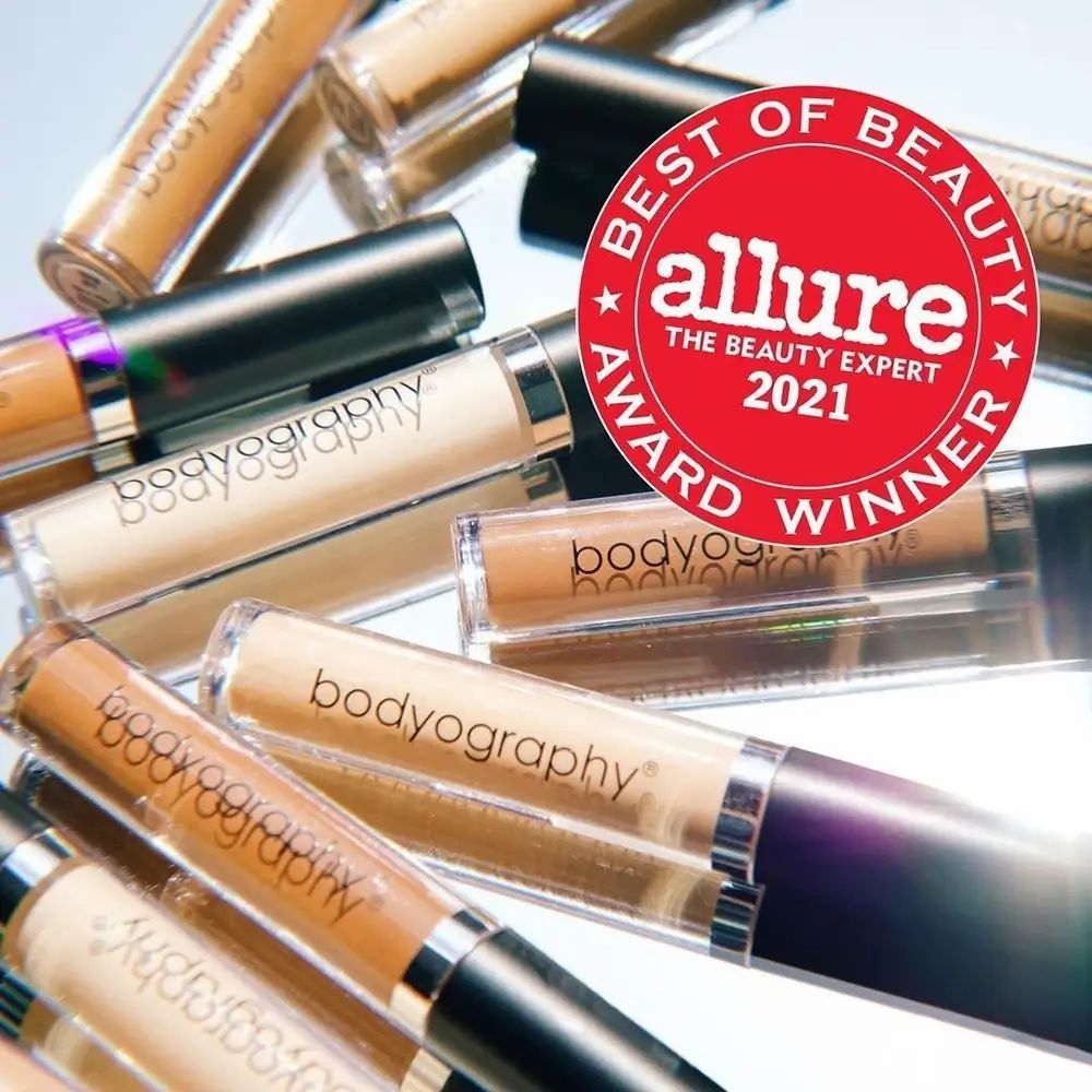 Meerdere concealer tubes op een spiegelend oppervlak. Rode sticker: Allure Best of Beauty Award Winner 2021. Opschrift: bodyography®.