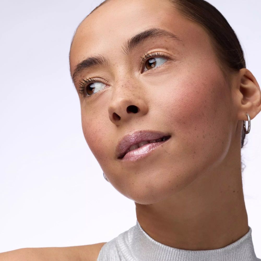 Portret van een vrouw met lipgloss op de lippen. Lichte huid, sproeten, zilveren top.