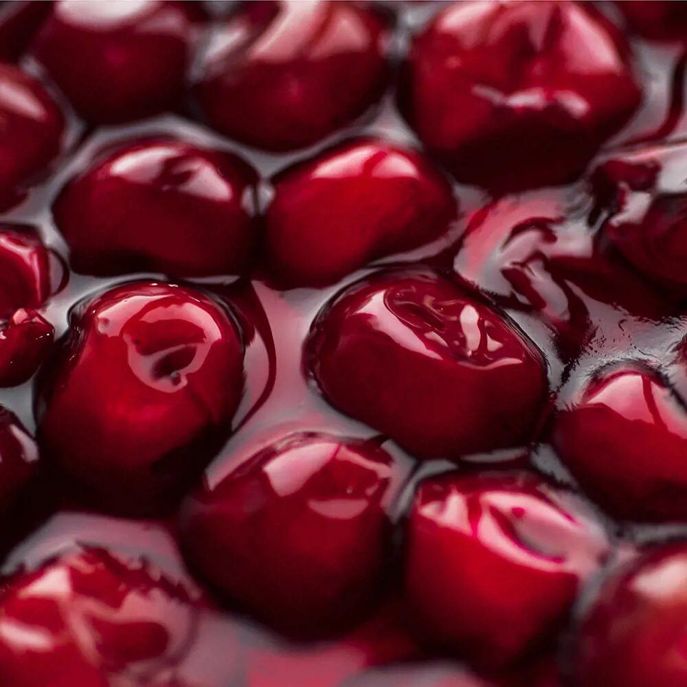 Close-up van rode kersen in vloeistof. Glanzend oppervlak, lichtspel.
