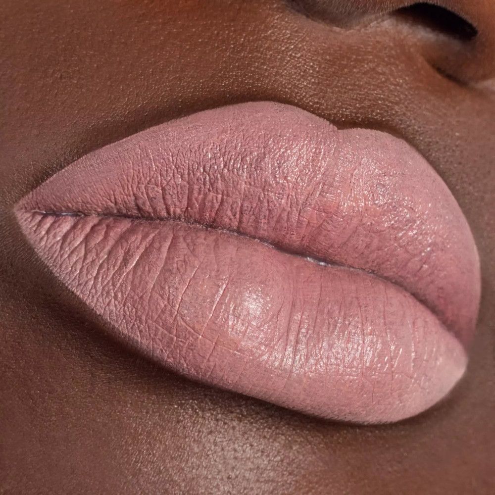 Gros plan sur des lèvres maquillées avec un rouge à lèvres rose clair. Les lèvres sont légèrement entrouvertes.