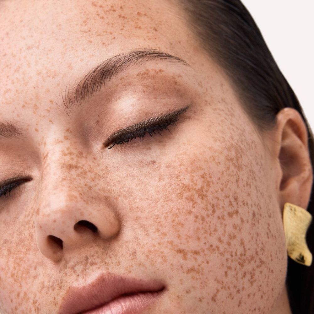 Close-up van een gezicht met sproeten. Gesloten ogen, eyeliner.