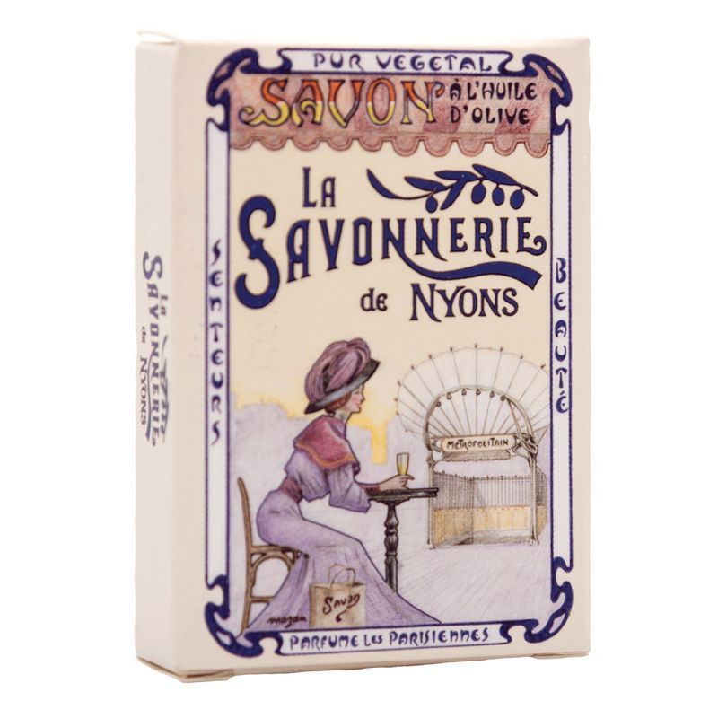 Zeep in kartonnen verpakking. Opschrift: La Savonnerie de Nyons. Illustratie van een vrouw aan een tafel.