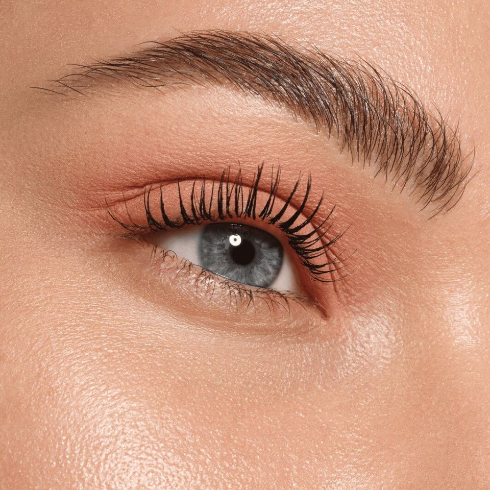 Close-up van een oog met roze oogschaduw. Blauwe ogen, donkere wimpers.