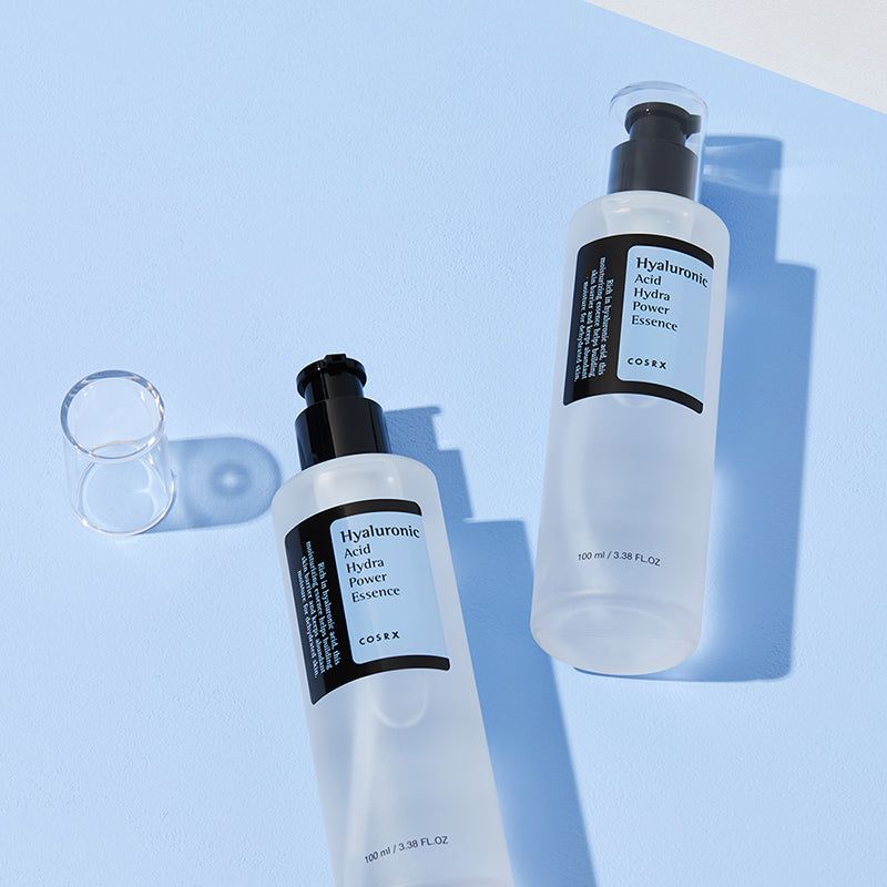 Twee flessen met pomp. Productnaam en merk COSRX op etiket. Op blauwe achtergrond.