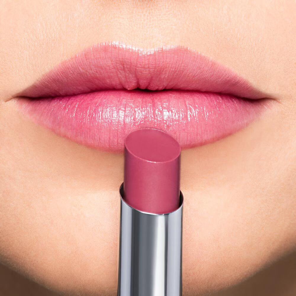 Close-up van lippen die een roze lippenbalsem ontvangen.