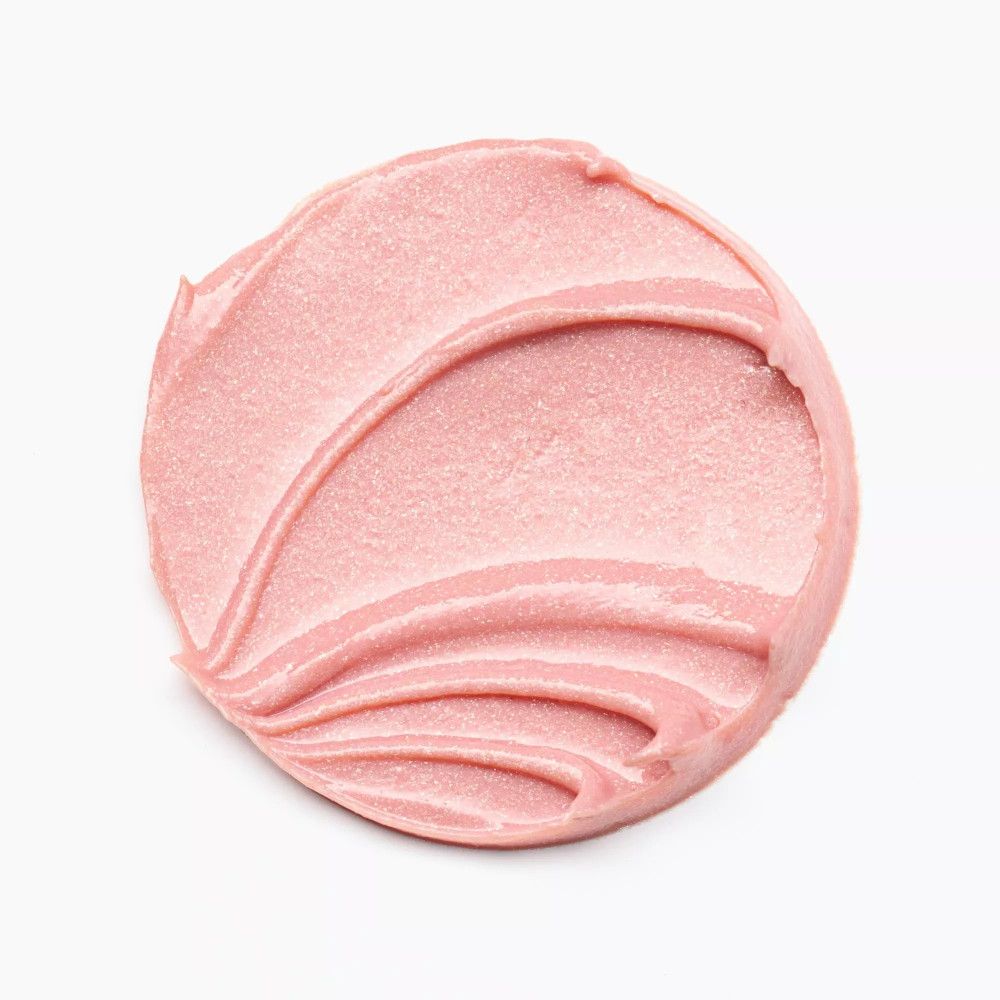 Roze lipbalsem-uitstrijkje op witte achtergrond. De textuur is romig en glanzend.