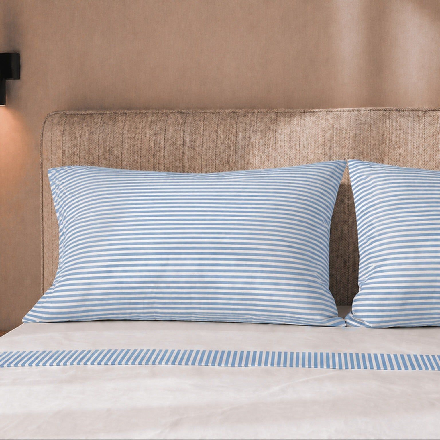 Twee gestreepte kussenslopen op een bed met gestreept dekbedovertrek.