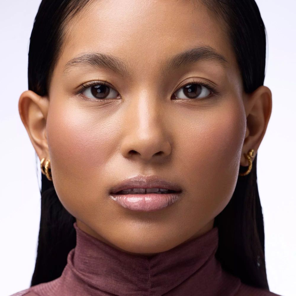 Portret van een vrouw met lipgloss. Ze draagt een bordeauxkleurige coltrui.