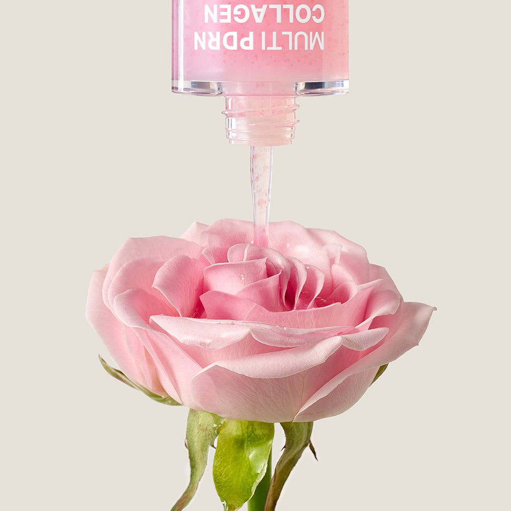 Serum druppelt uit druppelaar op een roze roos. Huidverzorgingsproduct.