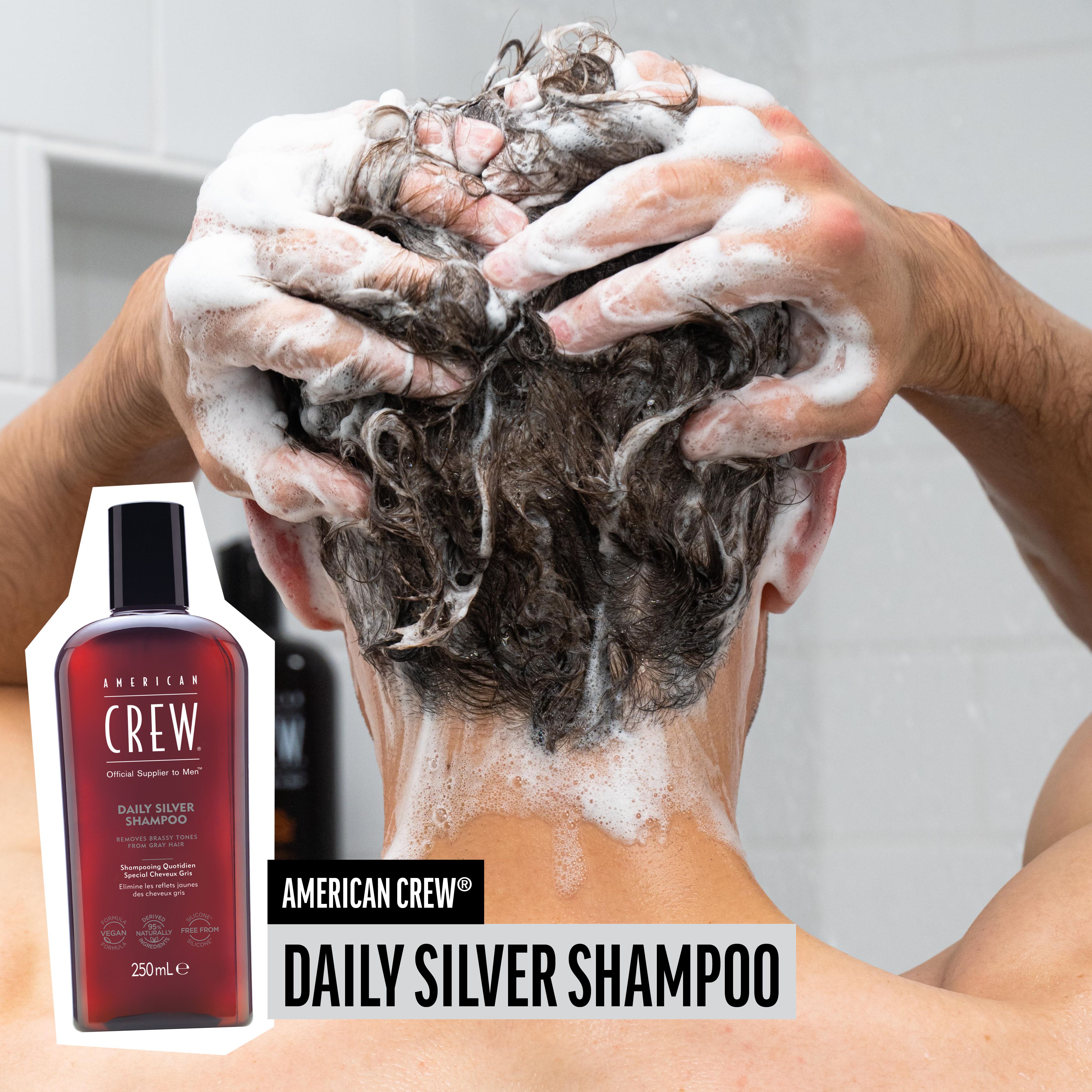 Homme se lavant les cheveux avec AMERICAN CREW Daily Silver Shampoo. Flacon en bas à gauche. Mousse sur la tête.