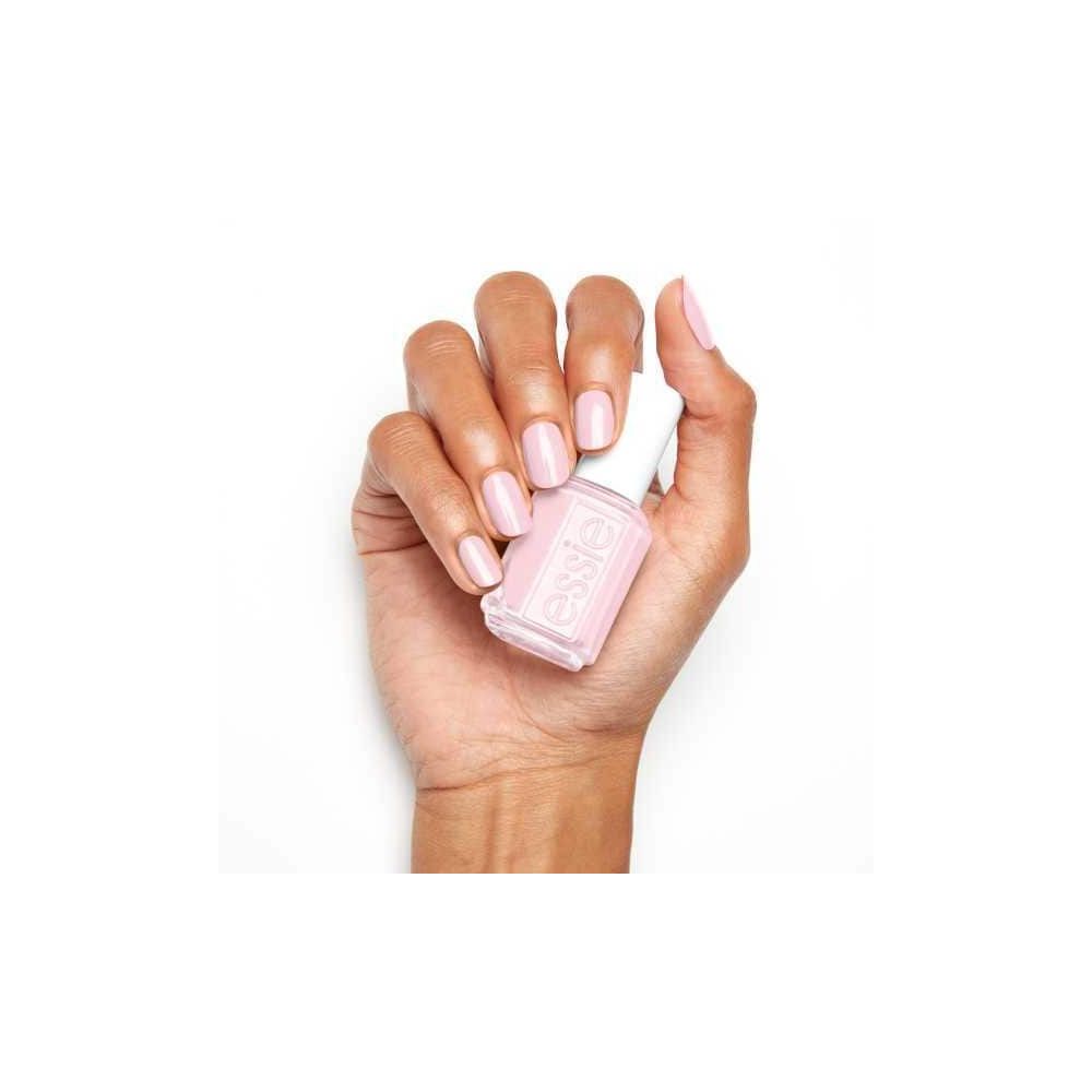 Hand houdt een flesje nagellak vast. Nagels gelakt in roze. Flesje met witte dop, opschrift 'essie'.