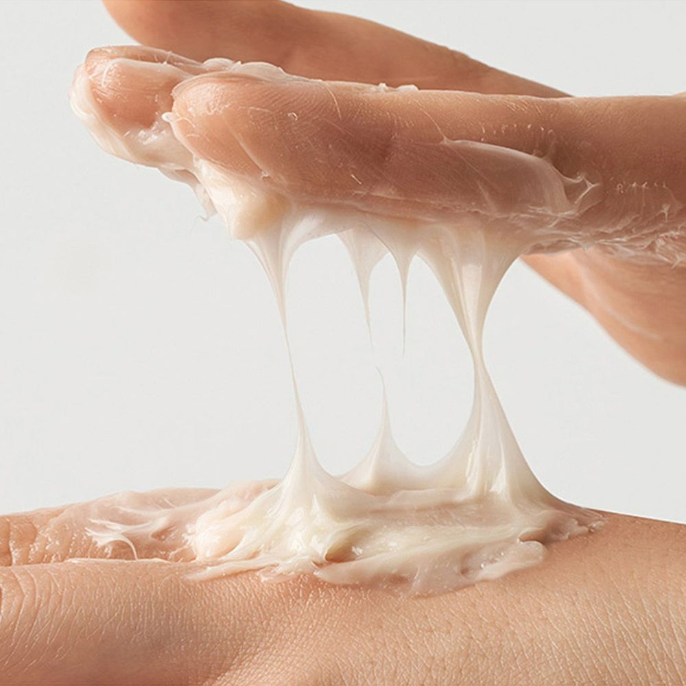 Mains avec substance crémeuse. La crème est blanche et forme des fils.