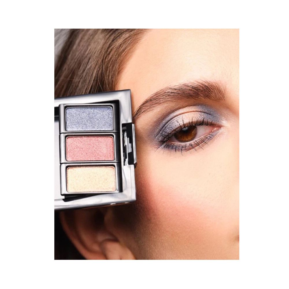 Palette de fards à paupières avec trois couleurs. Appliqué sur un œil. Boîtier argenté.