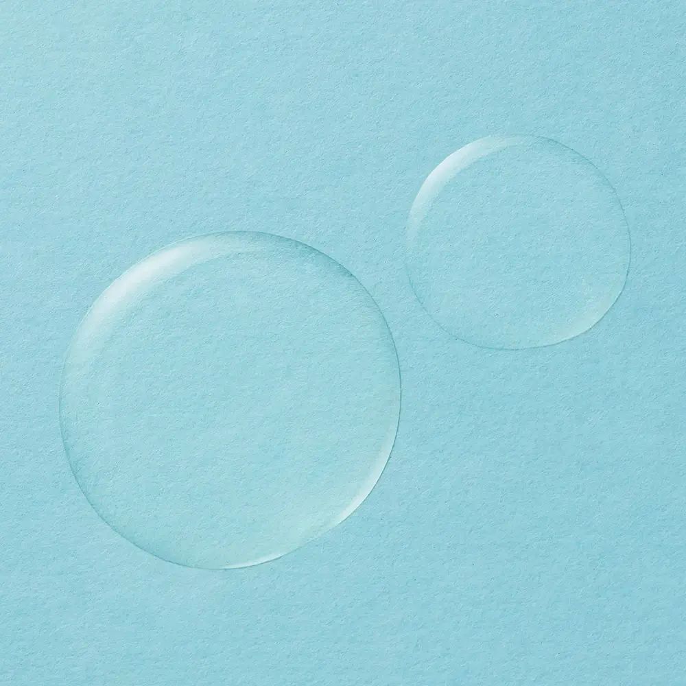 Twee druppels body oil op lichtblauwe achtergrond. Ronde vorm, transparante vloeistof.