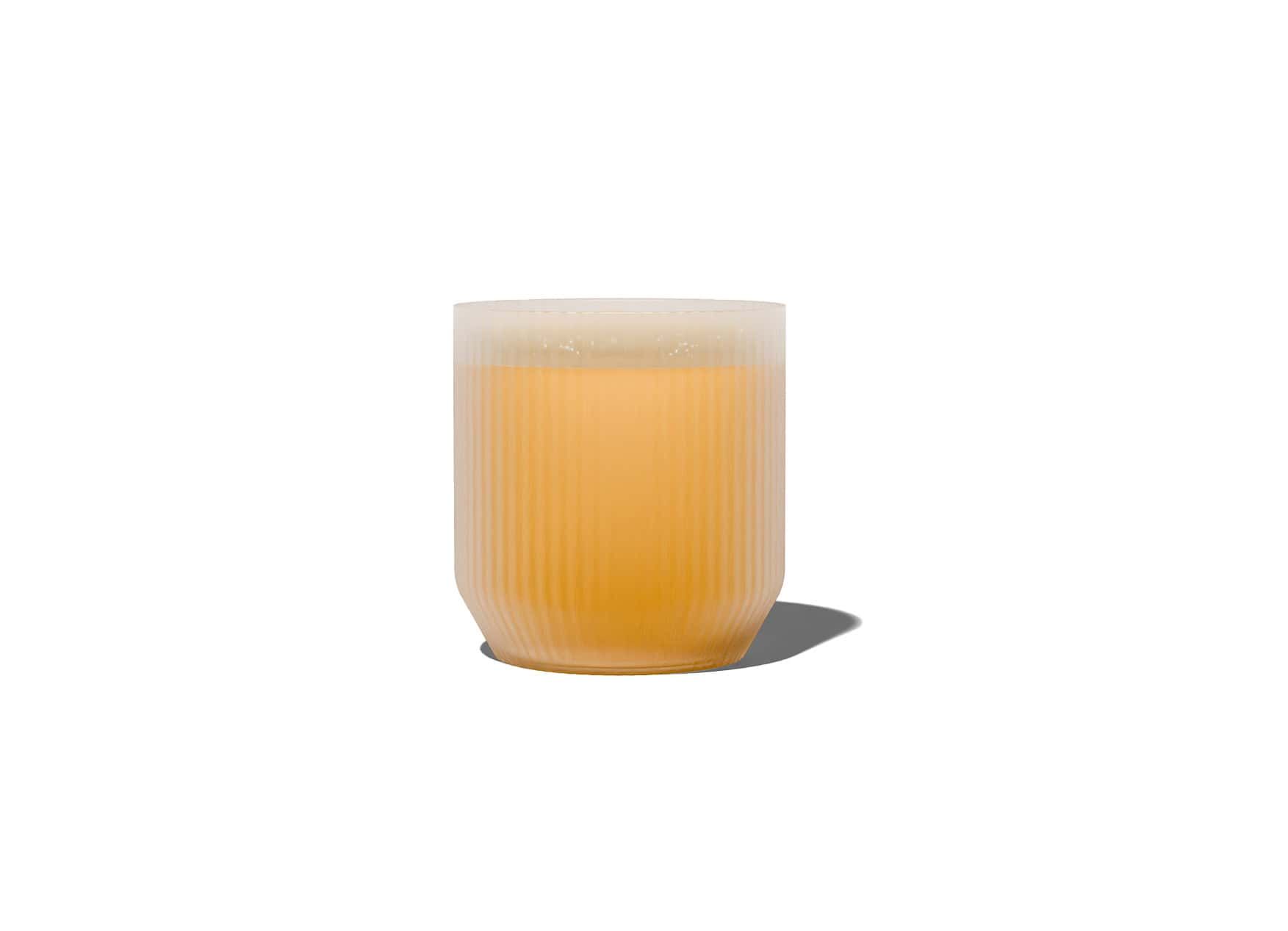 Bougie orange dans un récipient en verre dépoli côtelé avec un bord blanc.